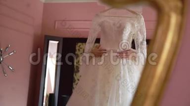新娘晨间准备.. 美丽的新娘穿着白色婚纱，穿着睡衣，抱着婚纱。 温柔时刻